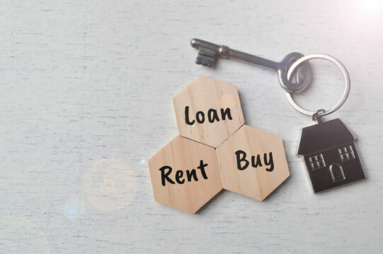 Mortgage loan options represented by wooden blocks with "Loan," "Rent," and "Buy" words, a house-shaped keychain, and a vintage key on a light wooden surface.